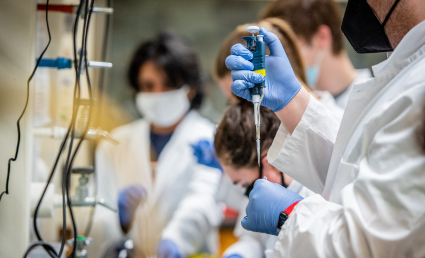 Stevens students working in the lab, one holding a syringe