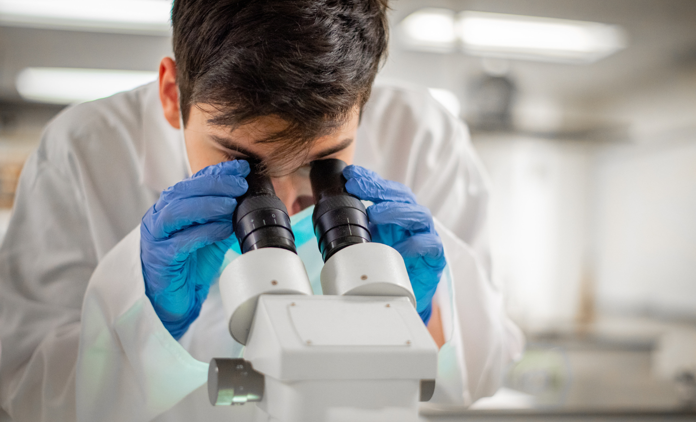 Biology student in lab looking through a microscope