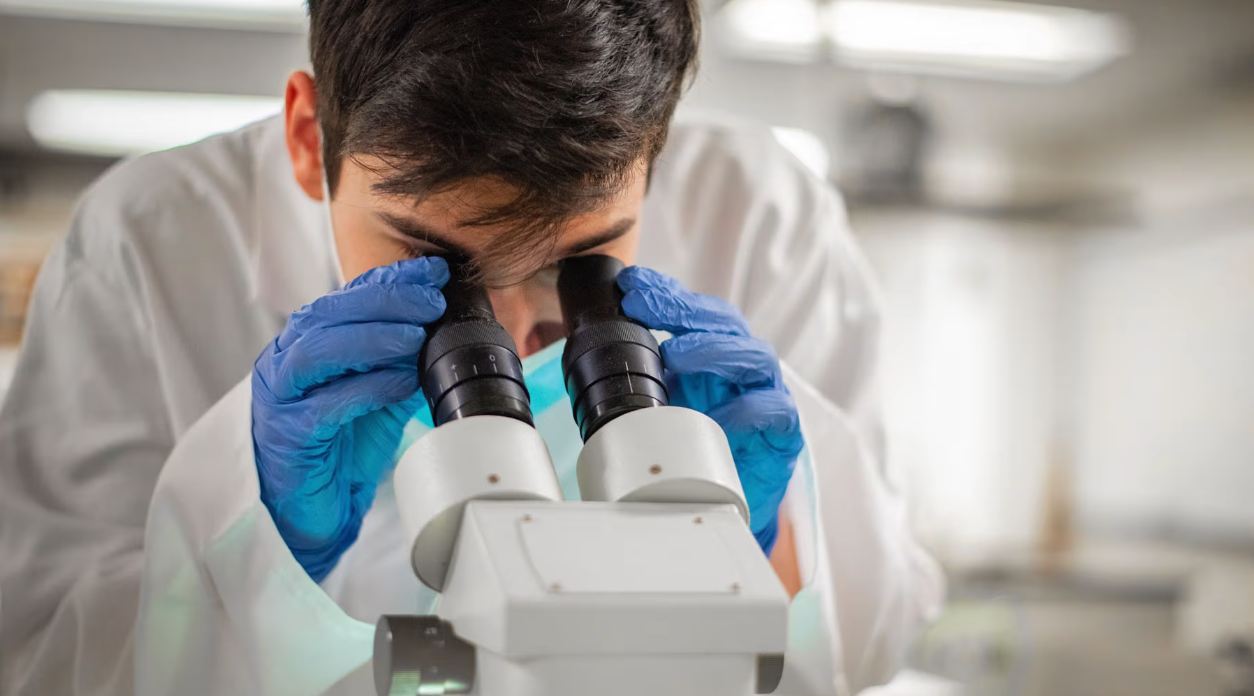 A student looking through a microscope.